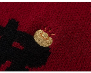 Detail of red knit sweater featuring premium golden embroidery and black knitted texture