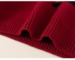 Close-up of red festive knit sweater featuring ribbed cuffs and soft wool texture