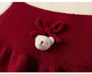 Close-up of knit dress featuring a plush 3D bear head and a cute red bow detail