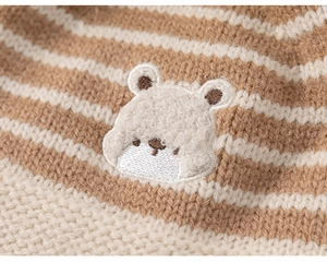 Detail of baby winter knit hat featuring striped pattern and a fuzzy bear patch