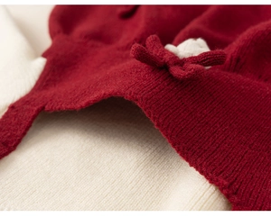 Close-up of red knit fabric featuring a decorative knit flower and ribbed hem detail