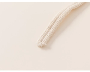 Detailed close-up of soft knitted cream-colored drawstring with rich braided texture