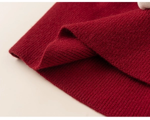 Close-up of deep red rib-knit sweater fabric showing thick wool texture and stitching