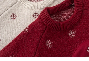 Detail of red and cream knit sweaters featuring festive snowflake patterns and ribbed neckline