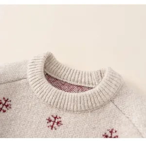 Detail of classic crew neck ribbing and red snowflake jacquard on beige knit sweater