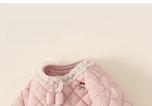 Vue détaillée de la veste matelassée rose avec broderie cerise et col en dentelle