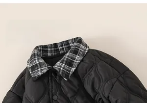 Detail of children's black quilted jacket featuring a checkered collar and BOBO embroidery
