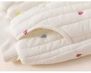 Détail du pantalon matelassé blanc avec broderies de cœurs colorés et bords-côtes
