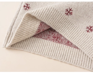 Macro shot of children's oatmeal knit sweater with red snowflake jacquard and ribbed hem