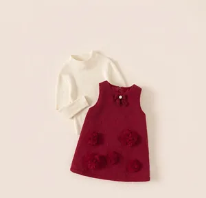 Close-up of girls' knit sweater and red tweed dress with bow and flower appliques