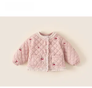 Détail de la veste matelassée rose avec broderie cerise et bordure en dentelle fine