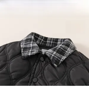 Detail of boys black quilted jacket showing plaid collar and BOBO letter embroidery