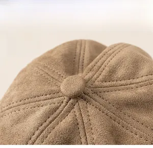 Detail of a brown suede baker boy hat showing a structured top and neat stitching