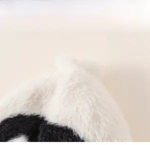 Close-up of fluffy black and white plush hat showing soft texture and structured crown