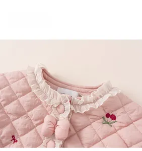 Détail de la veste matelassée rose pour fille avec broderie cerise et nœuds
