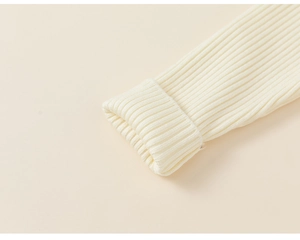Detailed close-up of ribbed knit cuffs on kids cream sweater with soft fabric texture