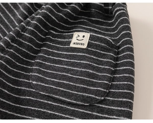 Détail de la texture du tissu gris rayé avec écusson visage souriant sur le pantalon