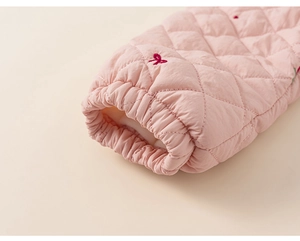 Détail de la manche matelassée rose avec poignet élastique et broderie nœud rouge fille