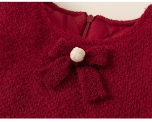 Detail of red winter dress with a knit bow, pompom, and quilted lining for toddlers