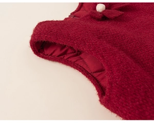 Detail of red tweed dress with quilted lining, featuring a bow and pearl bead accent
