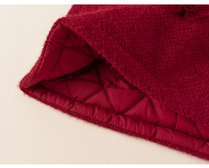 Close-up of red knit fabric with diamond quilted lining and floral detail