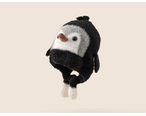Detail of penguin plush winter hat with earflaps and white pom-pom decorations