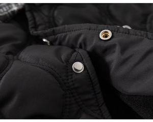 Detail view of black quilted winter jacket with premium metal snap button and stitching