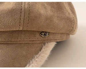 Detail of warm suede beret featuring soft plush lining and a vintage bronze metal tag
