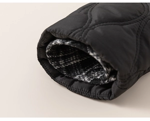 Detail of black quilted jacket cuff with a retro black and white checkered lining fabric