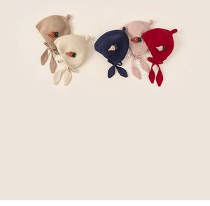 Detail view of five colors of knit ear-protection hats for kids with strawberry charms