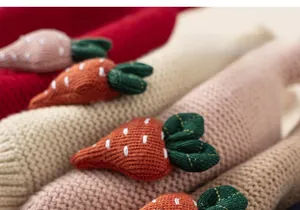 Close-up of a handmade 3D knitted carrot on a soft wool earflap hat for girls