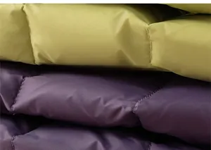 Detailed macro view of quilted fabric texture for kids down jacket in green and purple
