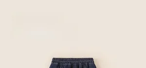 Detailed close-up of elastic waistband on dark blue children's denim jeans with orange stitching
