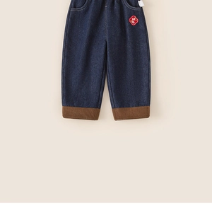 Close-up of boys denim pants featuring warm corduroy cuffs and traditional embroidery