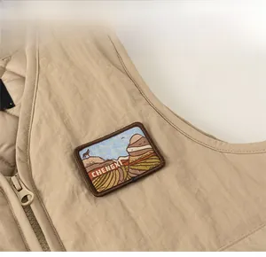 Close-up of khaki quilted vest featuring a mountain wolf embroidered patch and zipper