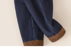 Detail of dark blue denim fabric with brown corduroy trim on children winter trousers