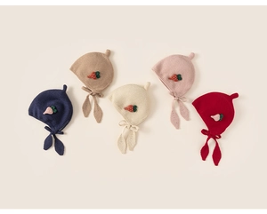 Flat lay of five colorful baby earflap hats with strawberry decor and leaf ties