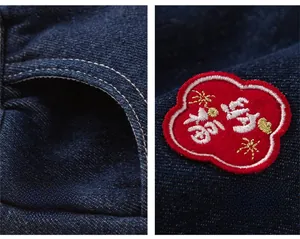 Detail of boys' winter jeans with dark blue denim fabric and red festive embroidery