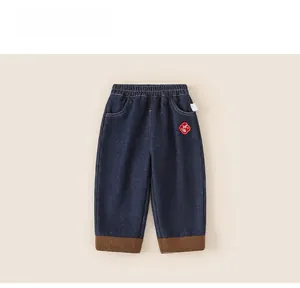 Detail of kids jeans with elastic waist and traditional red embroidery patch