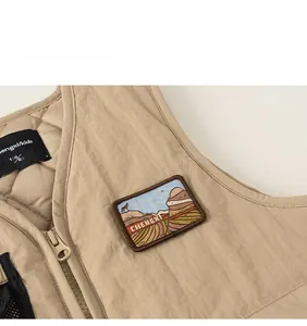 Detail of khaki quilted kids vest showing embroidered mountain patch and resin zipper