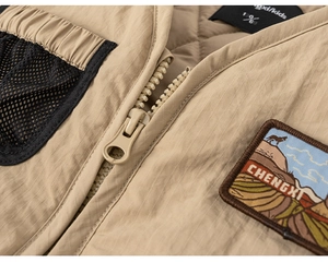 Detail of khaki kids cargo vest showing zipper, mesh pocket and embroidery patch