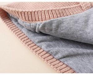 Detail of girls knit earflap hat showing the thick pink wool and soft grey inner lining