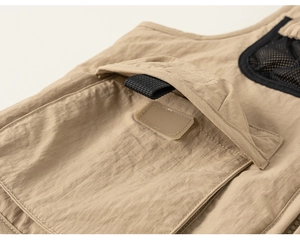 Detail shot of khaki utility vest showing ripstop fabric texture and velcro pocket flap