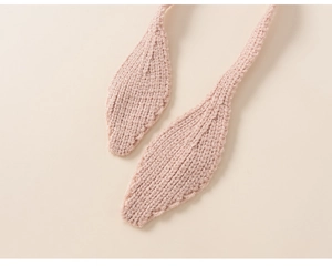 Close-up of pink hand-knitted baby hat ear flaps with scalloped lace edge detail