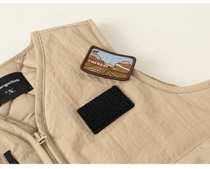 Detail of khaki kids cargo vest featuring mountain embroidery and warm quilted lining