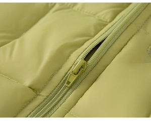 Detailed macro view of the matching green resin zipper on this quilted down jacket fabric