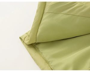 Detail of light green quilted down jacket showing fine stitching and smooth fabric texture