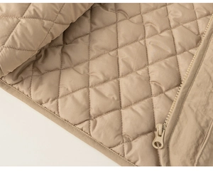 Detail shot of khaki diamond-quilted puffer vest featuring a matching resin zipper closure