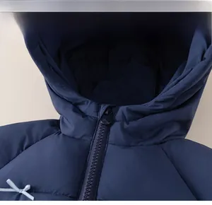 Detail of navy blue quilted puffer jacket showing zipper and blue ribbon bow decoration