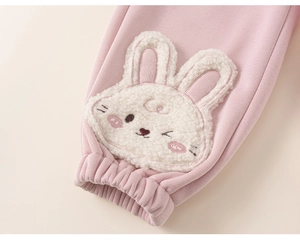 Detail of pink knitted toddler trousers featuring a plush bunny patch with embroidery